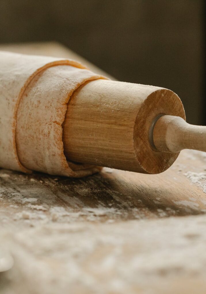 wooden rolling pin with dough on table